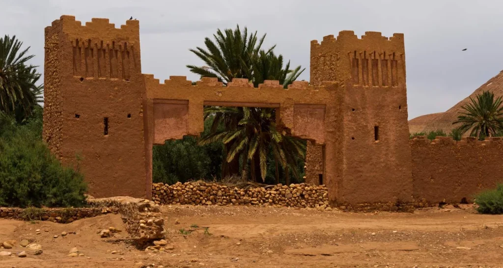 Tor von Aït Benhaddou mit Zwillingsverteidigungstürmen und Palmen hinter den Eingangsmauern