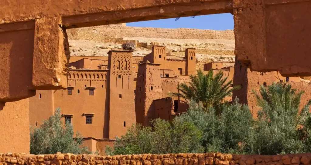 Lehmbauten und Palmen in Aït Benhaddou, umrahmt von einem traditionellen Torbogen aus Lehmziegeln