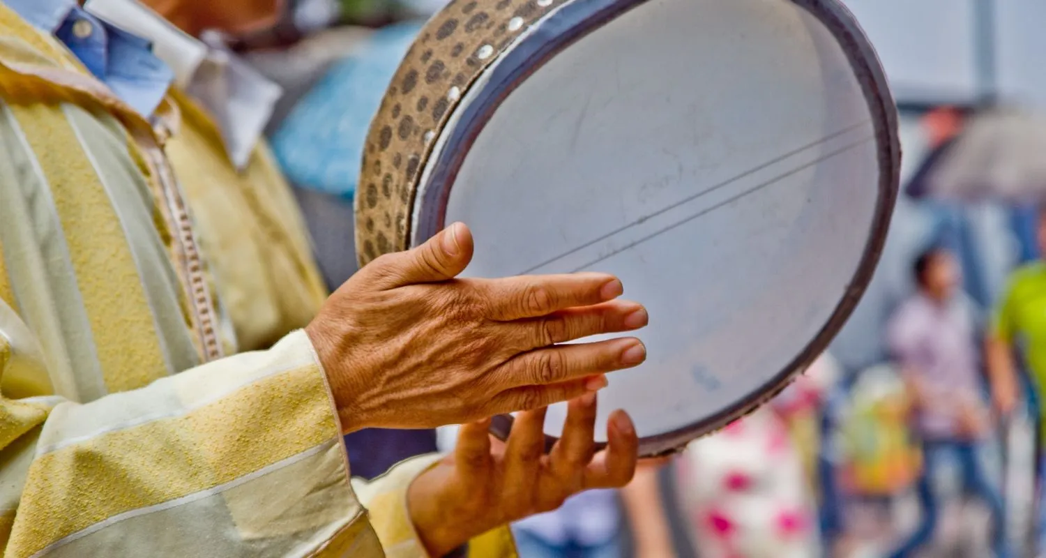 Musician's hands on a frame drum during a Sufi procession in Morocco